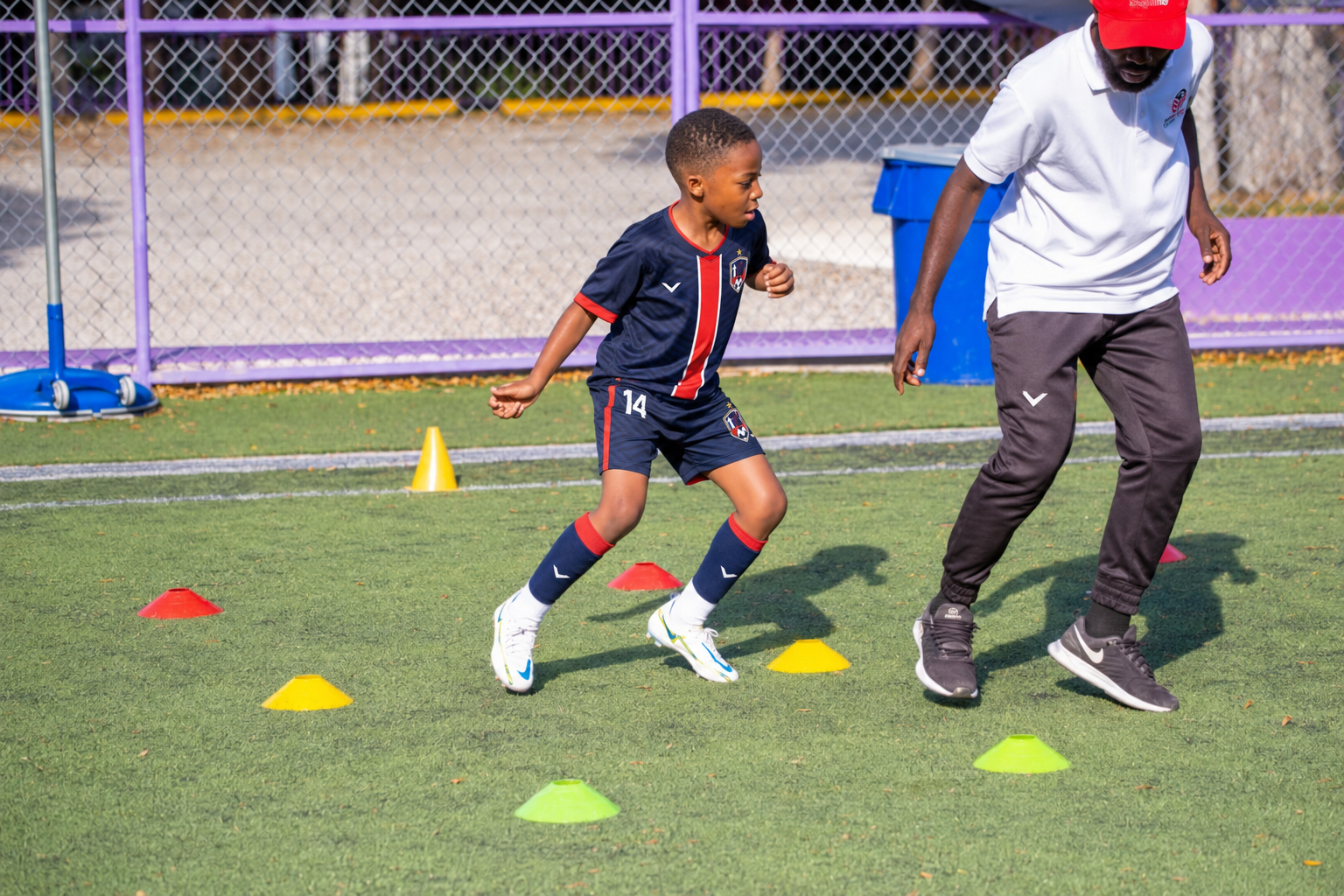 Coach supervising a young player during a structured training drill